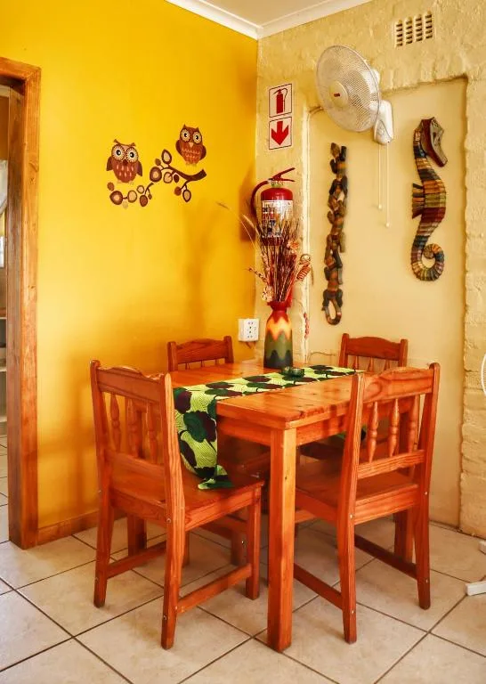 Bright yellow dining room with wooden table and chairs decorated with wall art