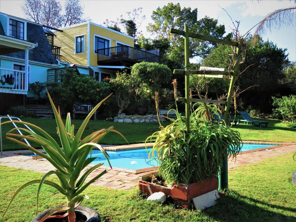 Colorful house with pool, lush gardens, and manicured lawn in sunshine