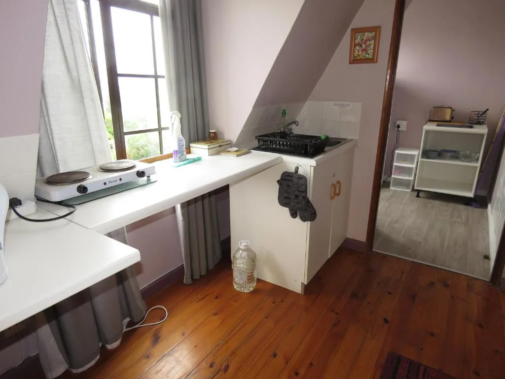 Compact kitchenette with white counters, small sink, and compact appliances in sloped attic room