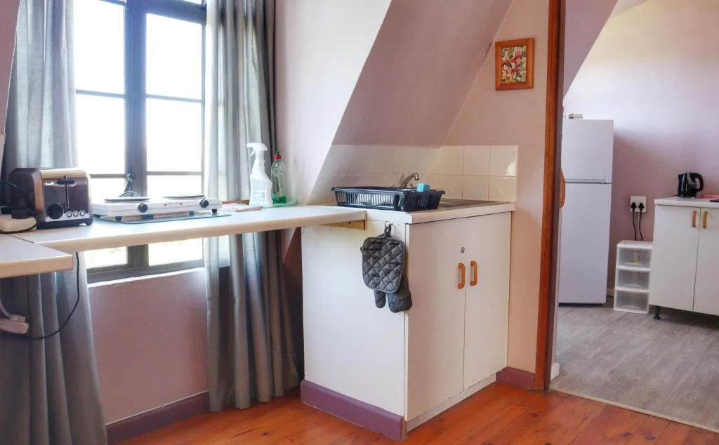 Compact kitchenette with white cabinetry, stove, and refrigerator in bright room