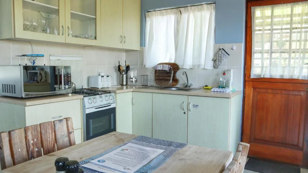 Light green kitchen cabinetry with stove, microwave, and dining table