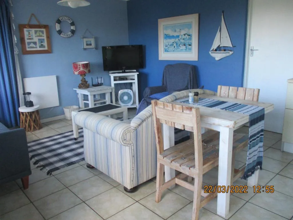 Blue-walled living room with striped armchair, TV, and nautical decor elements