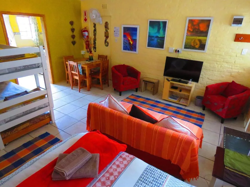 Bright yellow lounge with red sofas, TV, and colorful framed artwork