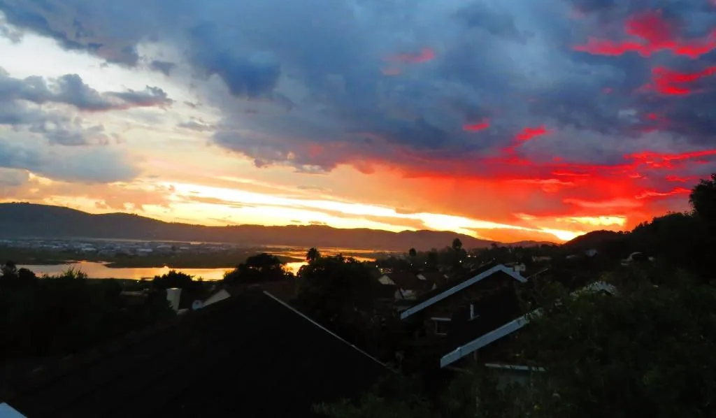 Dramatic sunset over Knysna Lagoon with mountains and residential homes silhouetted