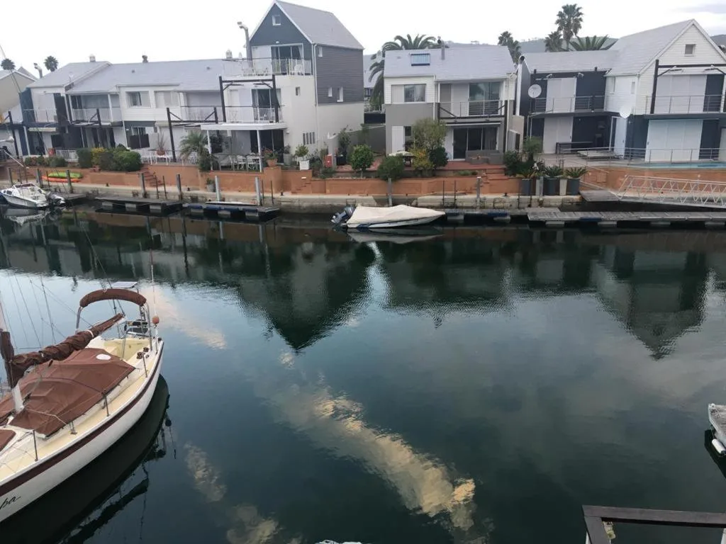 Waterfront properties overlooking calm lagoon with moored boats and palm trees