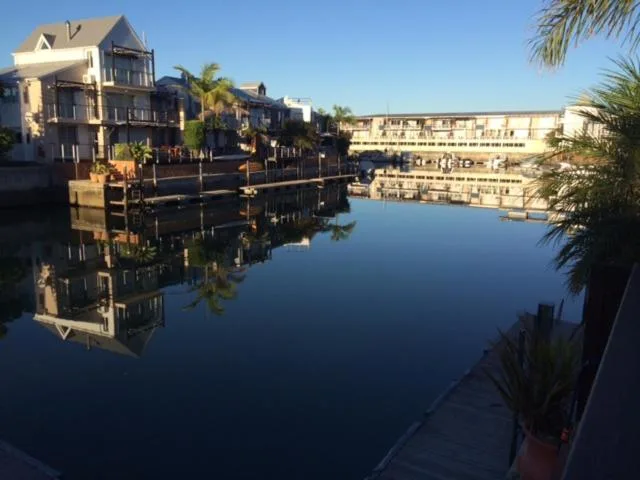Waterfront canal with apartment buildings reflected in calm blue water