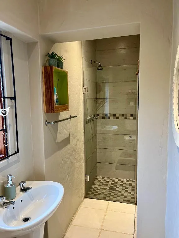 Modern bathroom with walk-in shower, white sink, and cream-colored tile walls