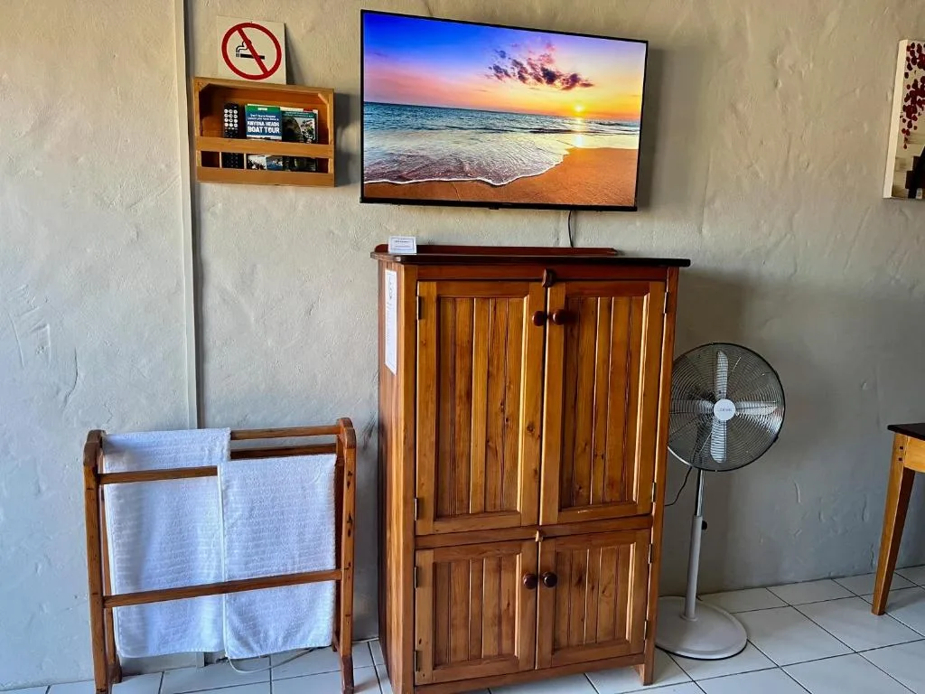 Bedroom amenities including wooden wardrobe, towel rack, and television display