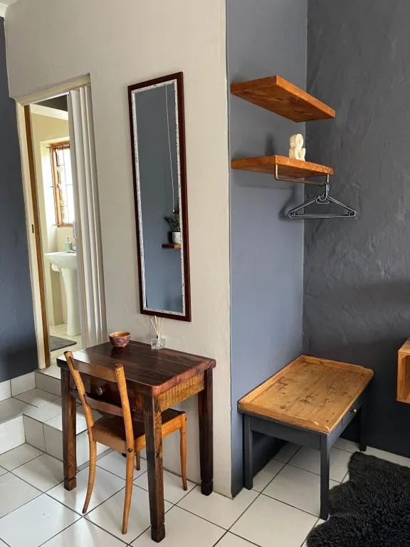 Wooden desk with chair, mirror, and floating shelves in bedroom alcove