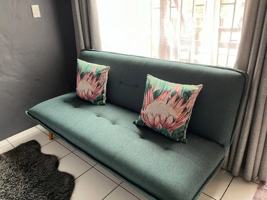 Modern green sofa with decorative floral pillows and natural light from windows