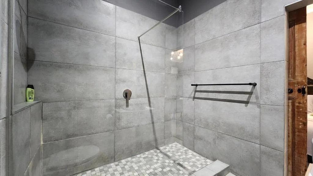 Modern walk-in shower with gray tiled walls and glass enclosure