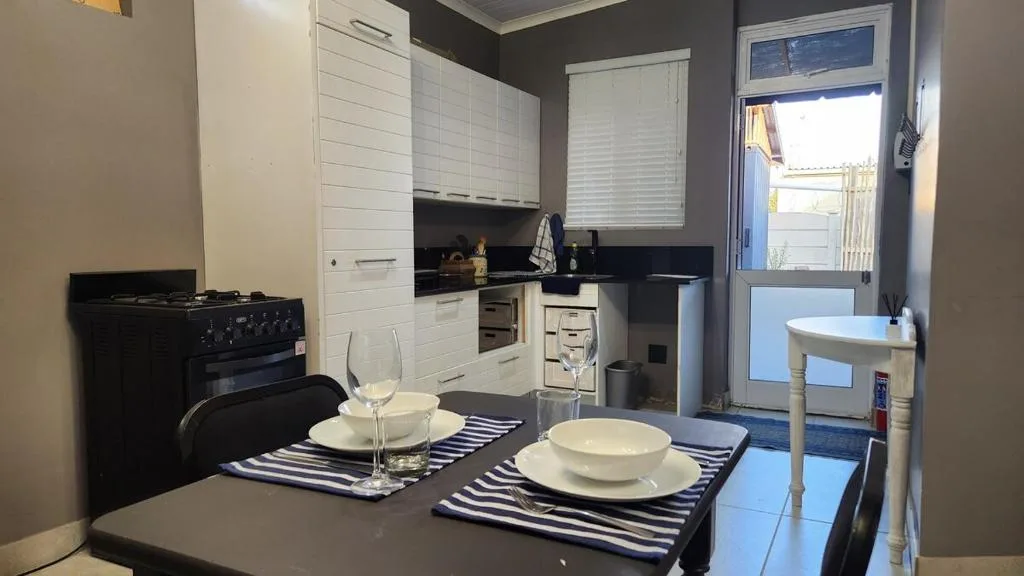 Dining table set for two with striped placemats and kitchenette beyond