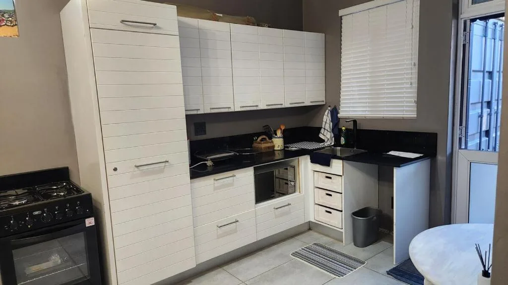 Modern kitchen with white cabinetry, black countertops, gas stove and built-in oven