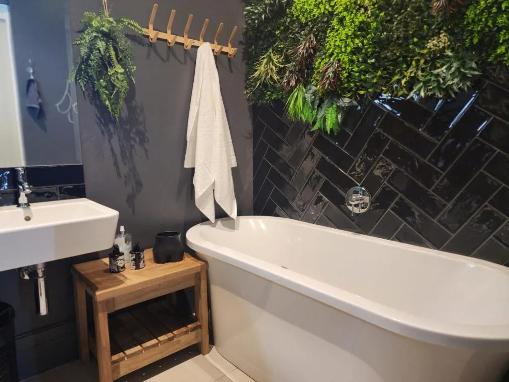 Modern bathroom with freestanding tub, sink, and living plant wall decor