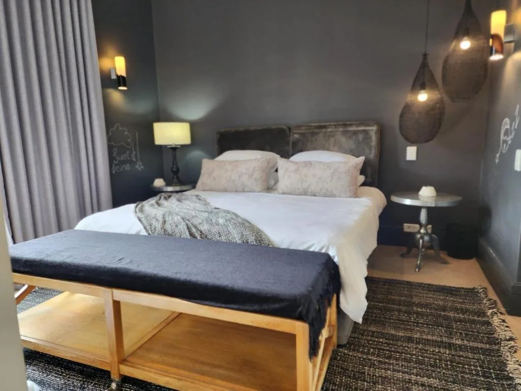 Modern bedroom with white bed, grey walls, pendant lights, and bench seating
