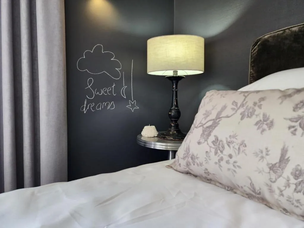 Cozy bedroom with floral pillow, bedside lamp, and sweet dreams wall art