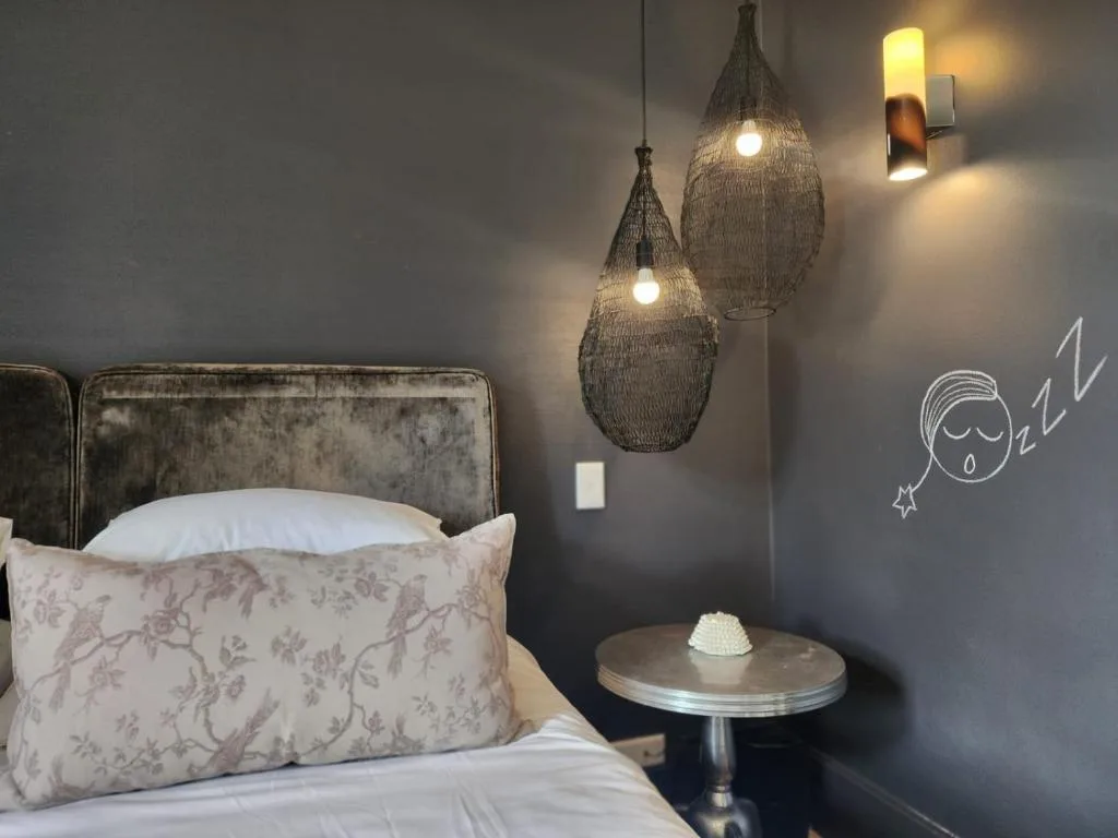 Modern bedroom with velvet headboard, pendant lights, and bedside table