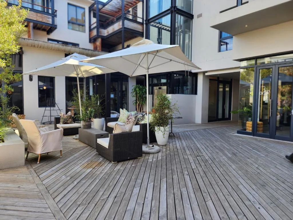 Modern outdoor patio with wooden decking, lounge chairs, umbrellas, and potted plants