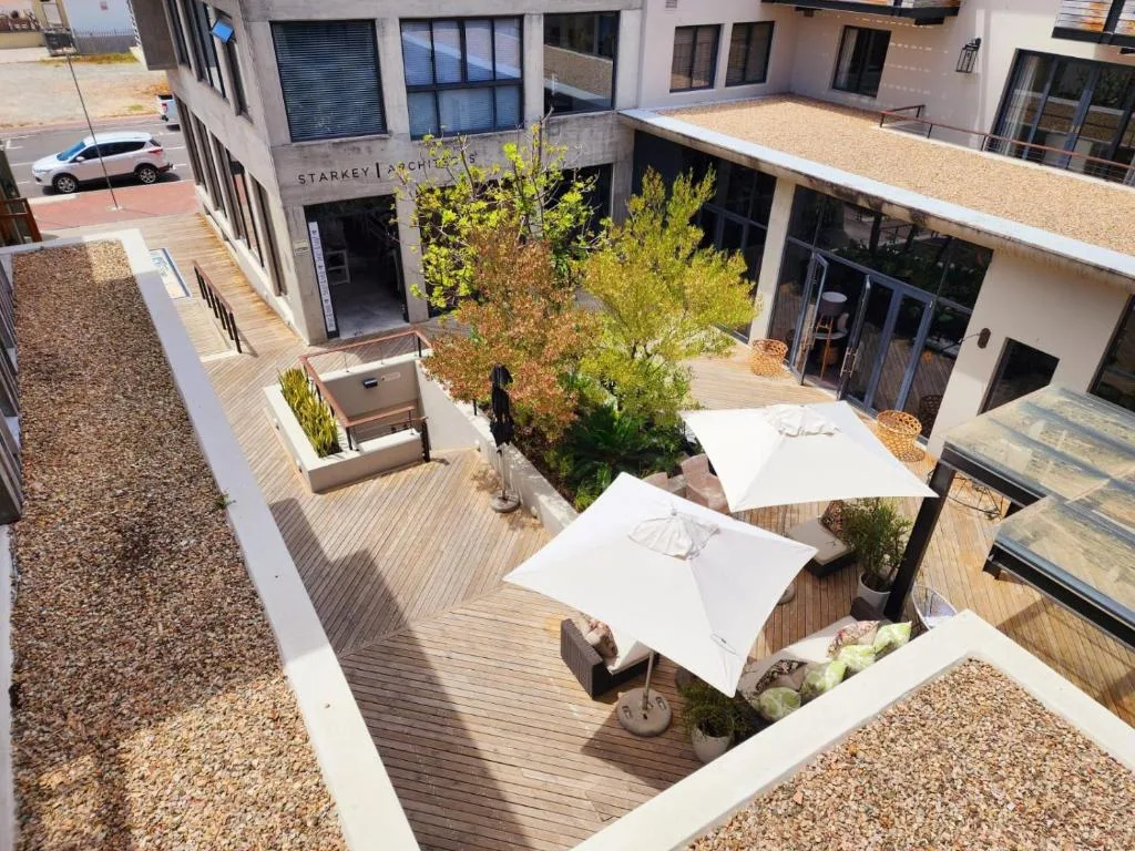 Contemporary courtyard with wooden deck, white umbrellas, and planted greenery