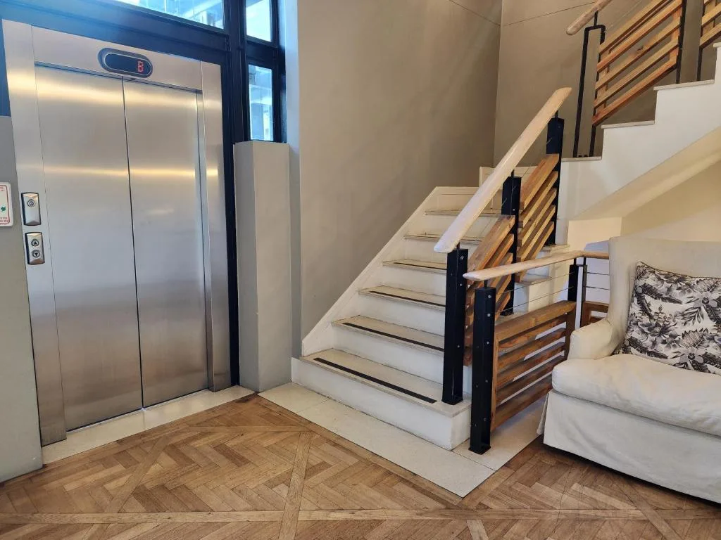 Modern staircase with wooden railings and elevator in contemporary lobby