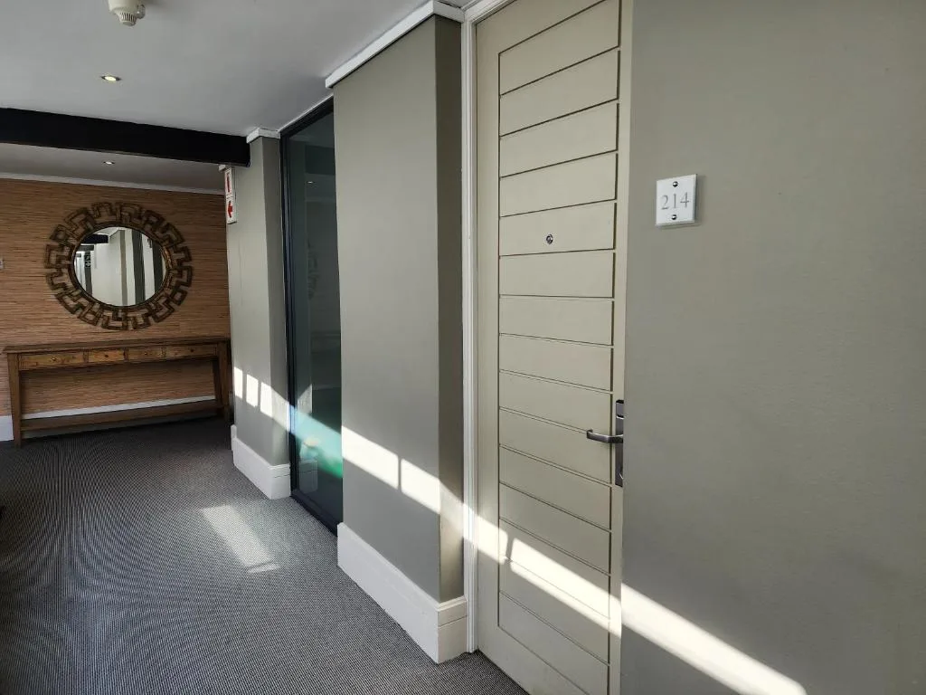 Modern hallway with wooden accent wall, circular mirror, and contemporary lighting fixtures