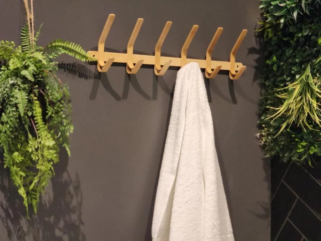 Wooden towel rack with white towel and hanging green plants