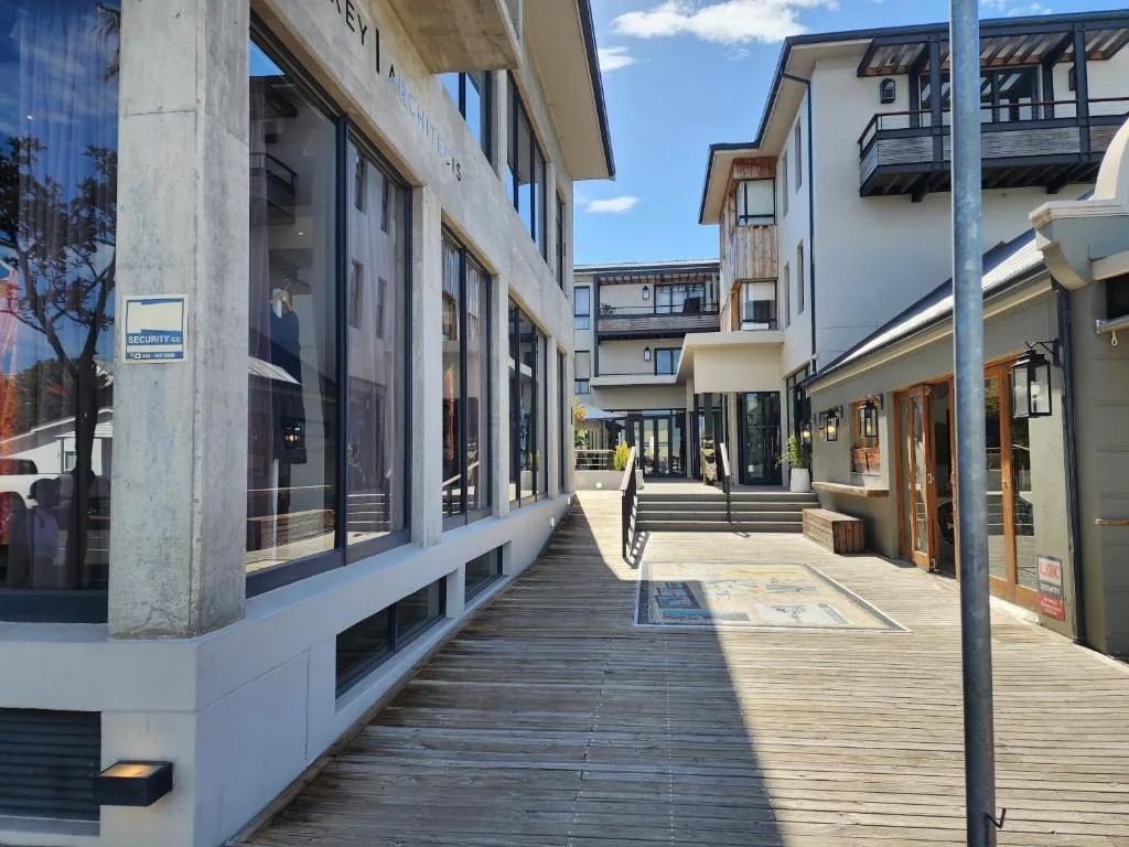 Modern apartment building exterior with wooden deck walkway and storefronts