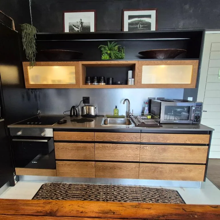 Modern kitchen with black stove, sink, microwave, wooden cabinetry and shelving