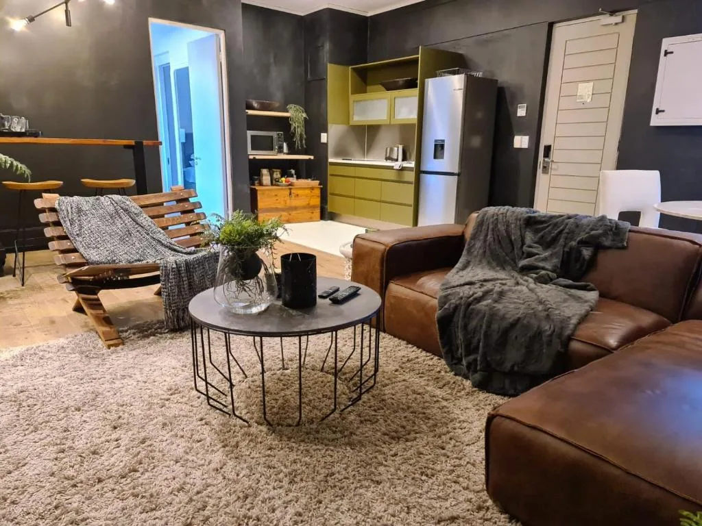Modern lounge with brown leather sofa, wooden chair, and round coffee table