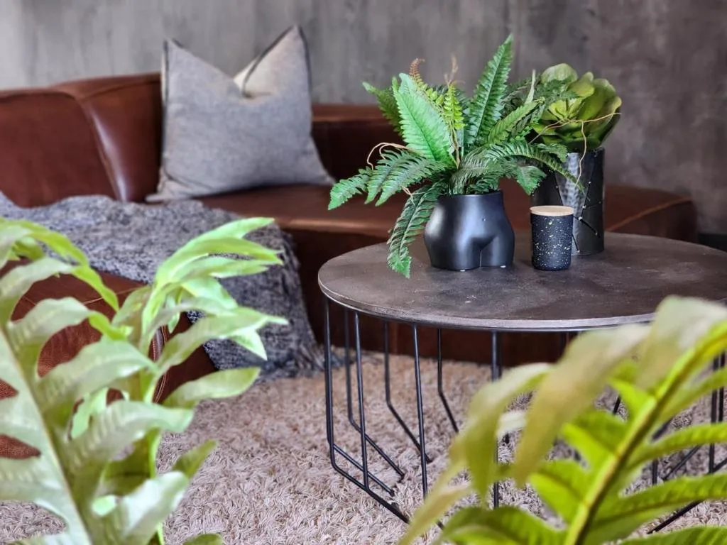 Modern lounge with brown leather sofa, potted plants, and contemporary decor