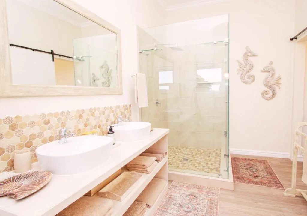 Modern bathroom with double vanity, mosaic tile backsplash, and glass shower enclosure