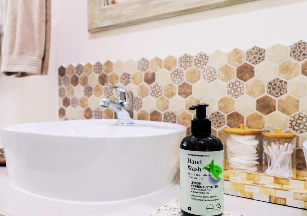 Modern bathroom with hexagonal tile backsplash, round white sink, chrome faucet