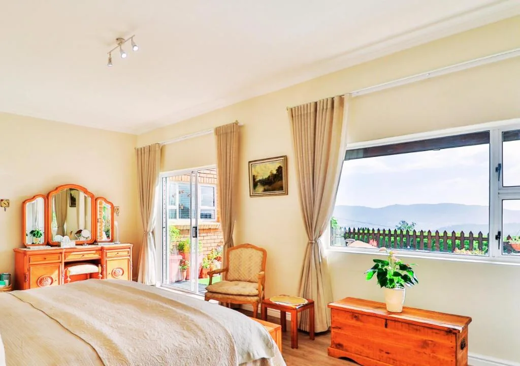 Bright bedroom with double bed, orange vanity, mountain views through windows