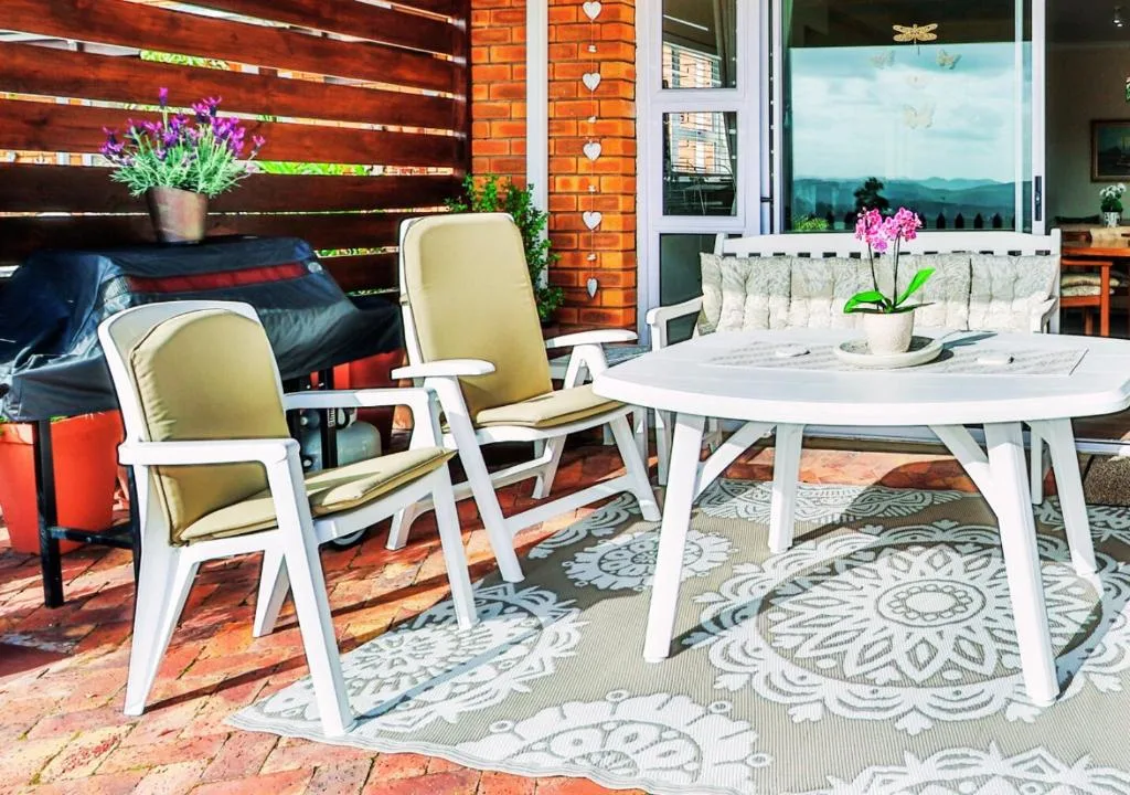 Outdoor patio with white table, cushioned chairs, and mountain views