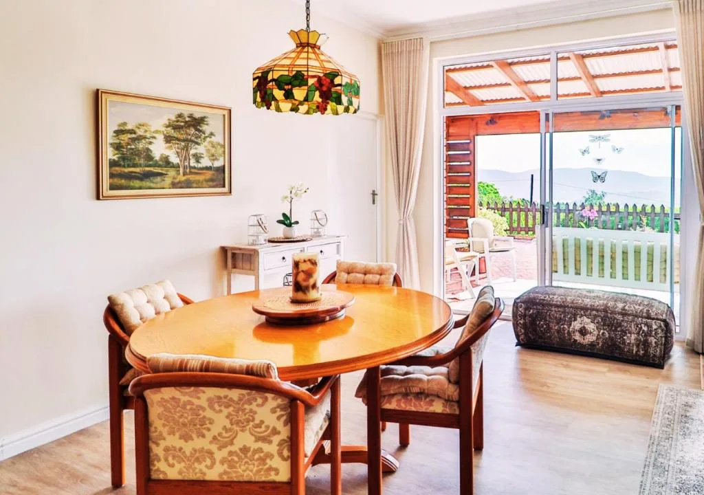 Warm dining room with round wooden table and ocean view through glass doors