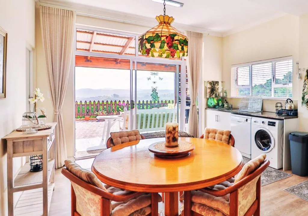 Round wooden dining table with upholstered chairs and mountain views beyond