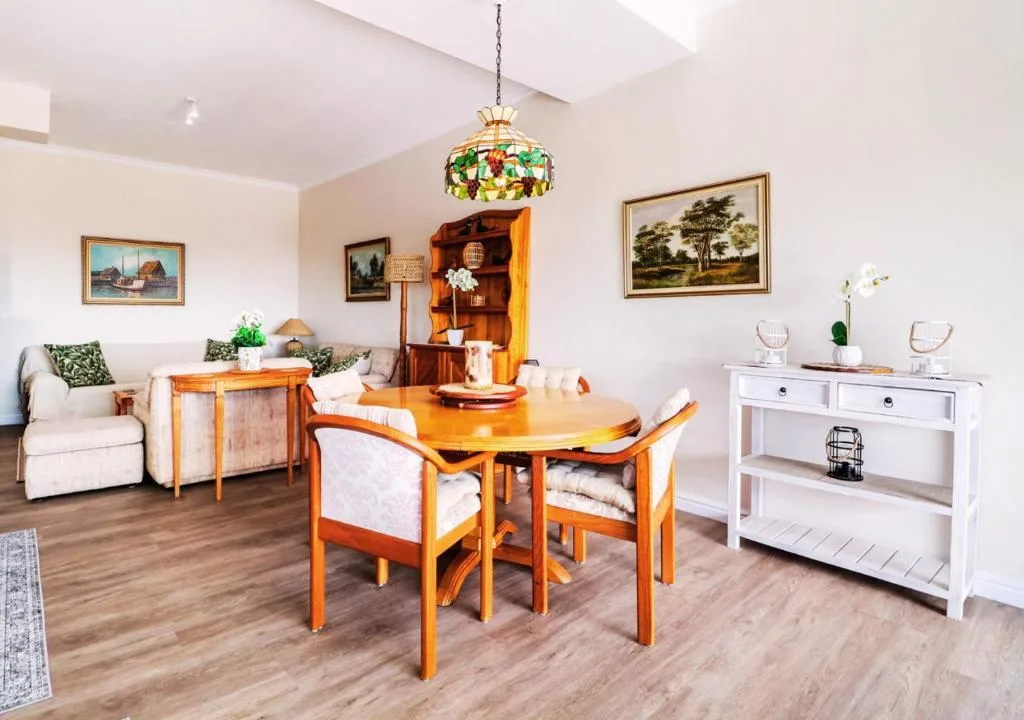 Bright dining area with wooden table, chairs, and lounge seating visible
