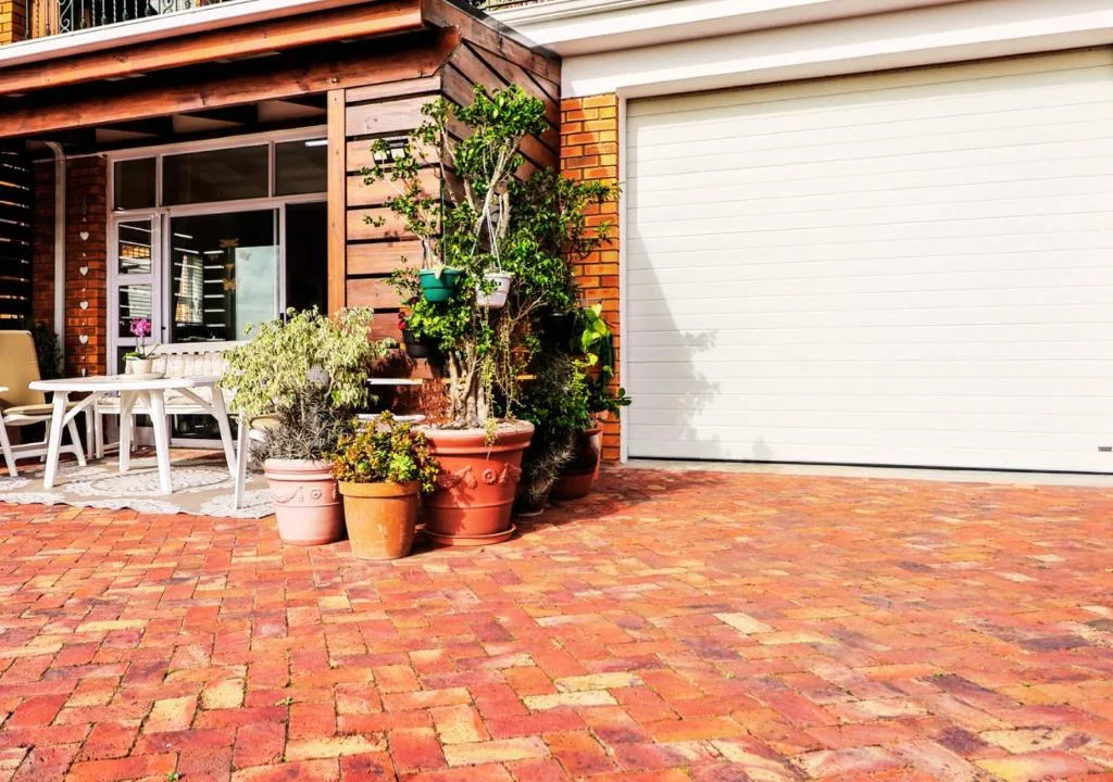 Brick patio with potted plants and white outdoor furniture near entrance