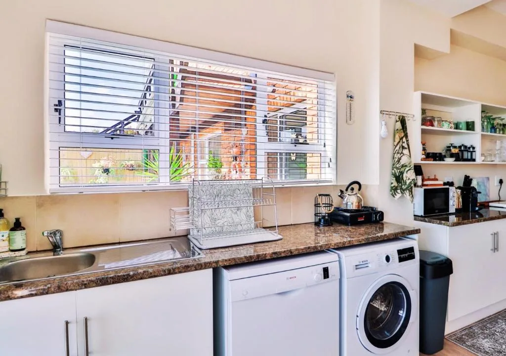 Modern kitchen with granite countertops, stainless sink, dishwasher, and washing machine