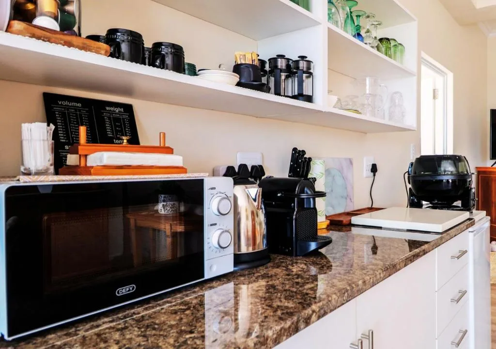 Modern kitchen with granite countertop, microwave, and organized open shelving