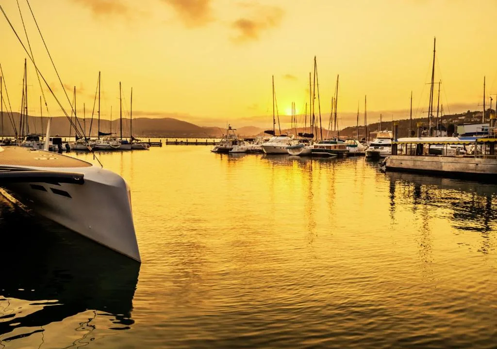 Golden sunset over Knysna Heads with moored sailboats and yacht harbor