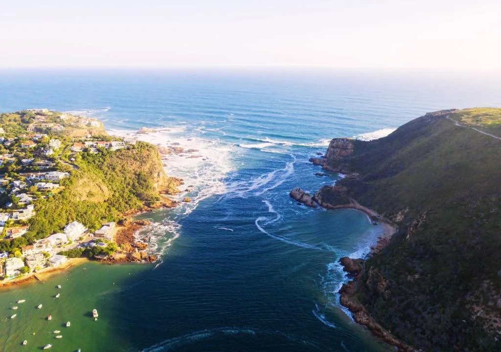 Aerial view of Knysna coastline with emerald bay and rocky cliffs