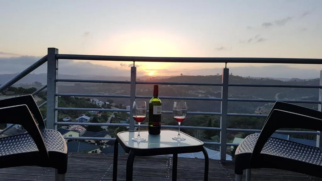 Sunset vista over Knysna lagoon and valley from elevated deck with wine
