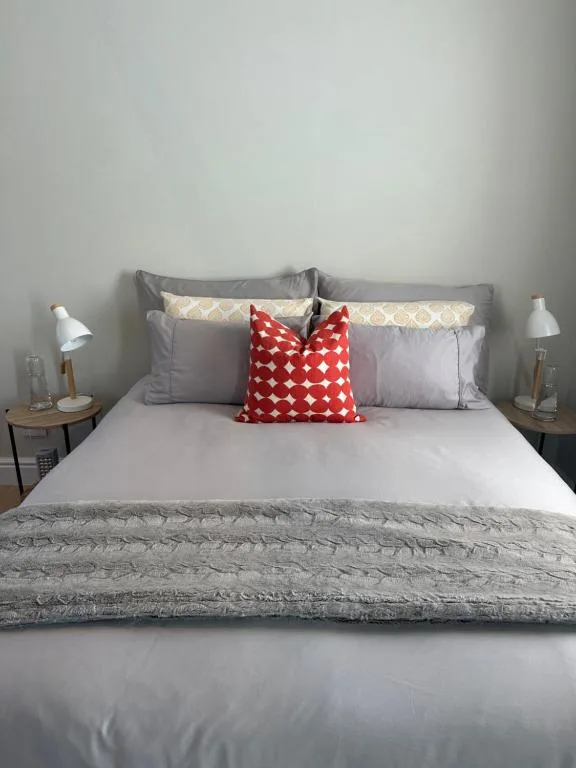 Modern bedroom with queen bed, gray bedding, and red decorative pillow