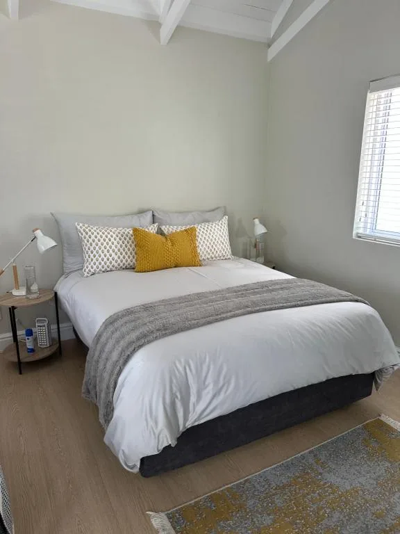 Bright bedroom with queen bed, patterned pillows, gray throw blanket