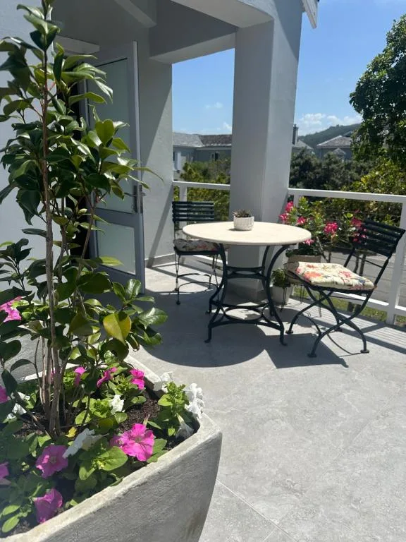 Sunny outdoor deck with dining table, flowering plants, and mountain views