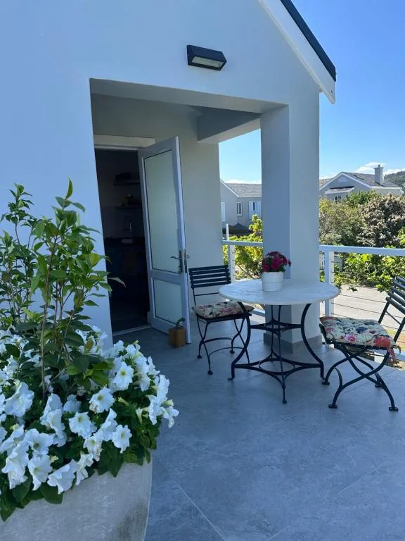 Covered patio with dining table, chairs, and white flowering plants overlooking town