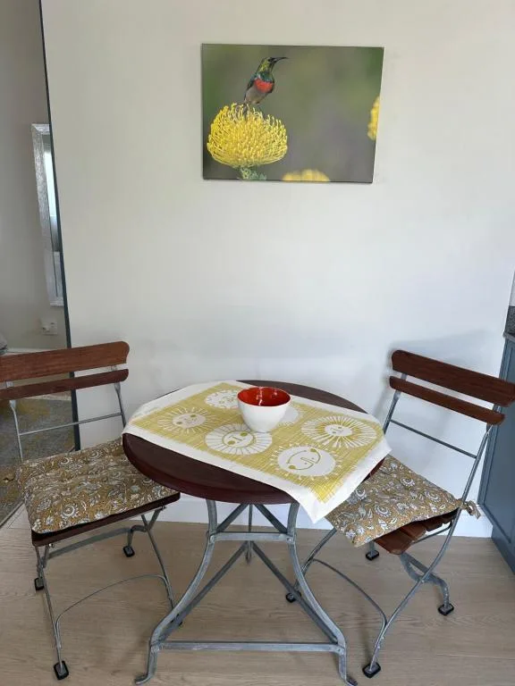 Compact dining area with small table, chairs, and hummingbird artwork