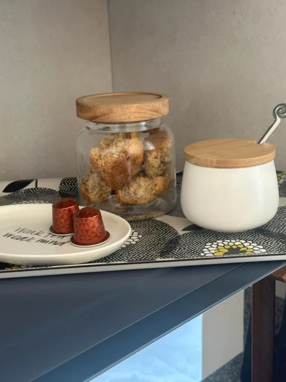 Kitchen counter with glass cookie jar, ceramic container, and coffee cups