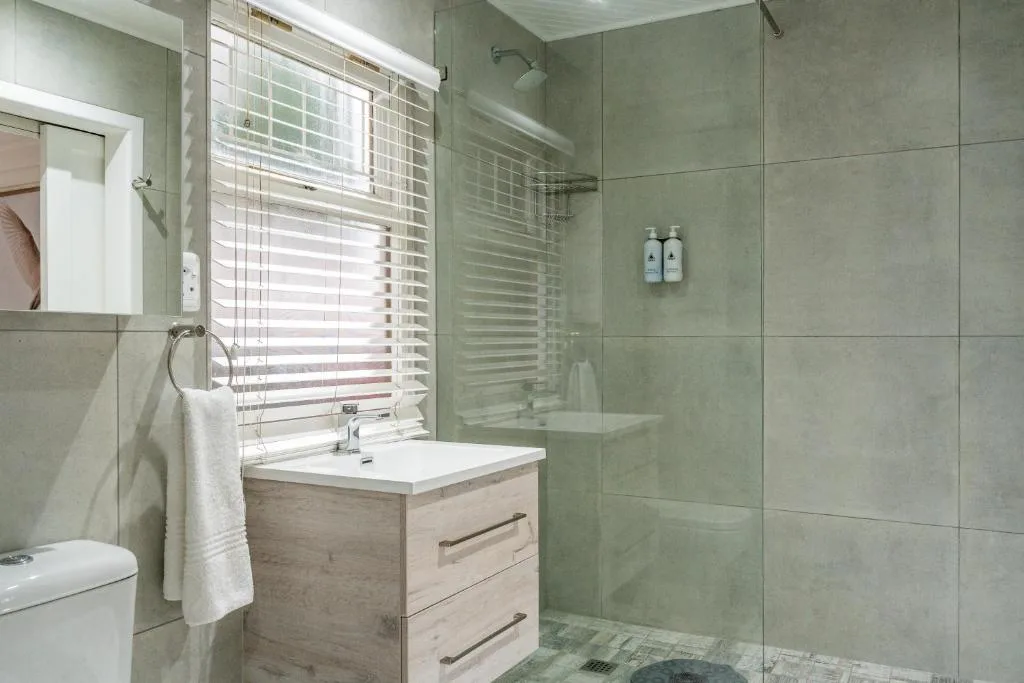 Modern bathroom with walk-in shower, vanity, and natural light from window